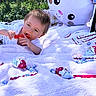 baby, blanket, candy, child, chocolate, cute, easter, egg, grass, inflatable, kinder, lying, outdoor, person, play, plush, red, smiling, toy, white