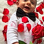 baby, infant, smile, bow_tie, rose_petals, red_rose, white_blanket, lying_down, onesie, close_up, happy, cute, face, eyes, hand, green_leaf, flower, portrait, soft_texture, red