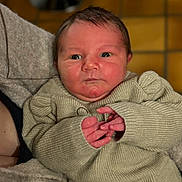 Hugo participe au concours pour gagner de l'argent avec cette photo : newborn, baby, infant, sweater, hands, face, person, portrait, indoors, closeup, skin, expression, warm_lighting, cozy, cute, young_child, knitwear, human, head, candid