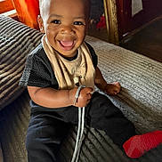 Amirion is registered to the contest to win money with this photo: toddler, child, smiling, happy, indoor, couch, clothing, black_shirt, black_pants, red_socks, shoelace, curtain, window, home, portrait, sitting, face, baby, cute, person