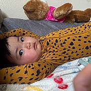 Ria is registered to the contest to win money with this photo: baby, infant, child, bed, blanket, plush_toy, teddy_bear, onesie, leopard_print, sleepwear, cozy, soft_texture, indoors, cute, lying_down, portrait, expression, face, comfort, resting