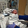 Ari Natasha is registered to the contest to win money with this photo: newborn, baby, hospital, medical_equipment, blanket, gloves, infant, sleeping, bed, person, healthcare, monitor, striped, nursery, patient, care, clinic, blue_gloves, swaddled, quiet