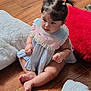 toddler, child, baby, pigtails, indoor, wooden_floor, cushions, pastel_bib, dress, sitting, barefoot, curious, soft_toys, floor, cute, young_child, person, portrait, home, cozy