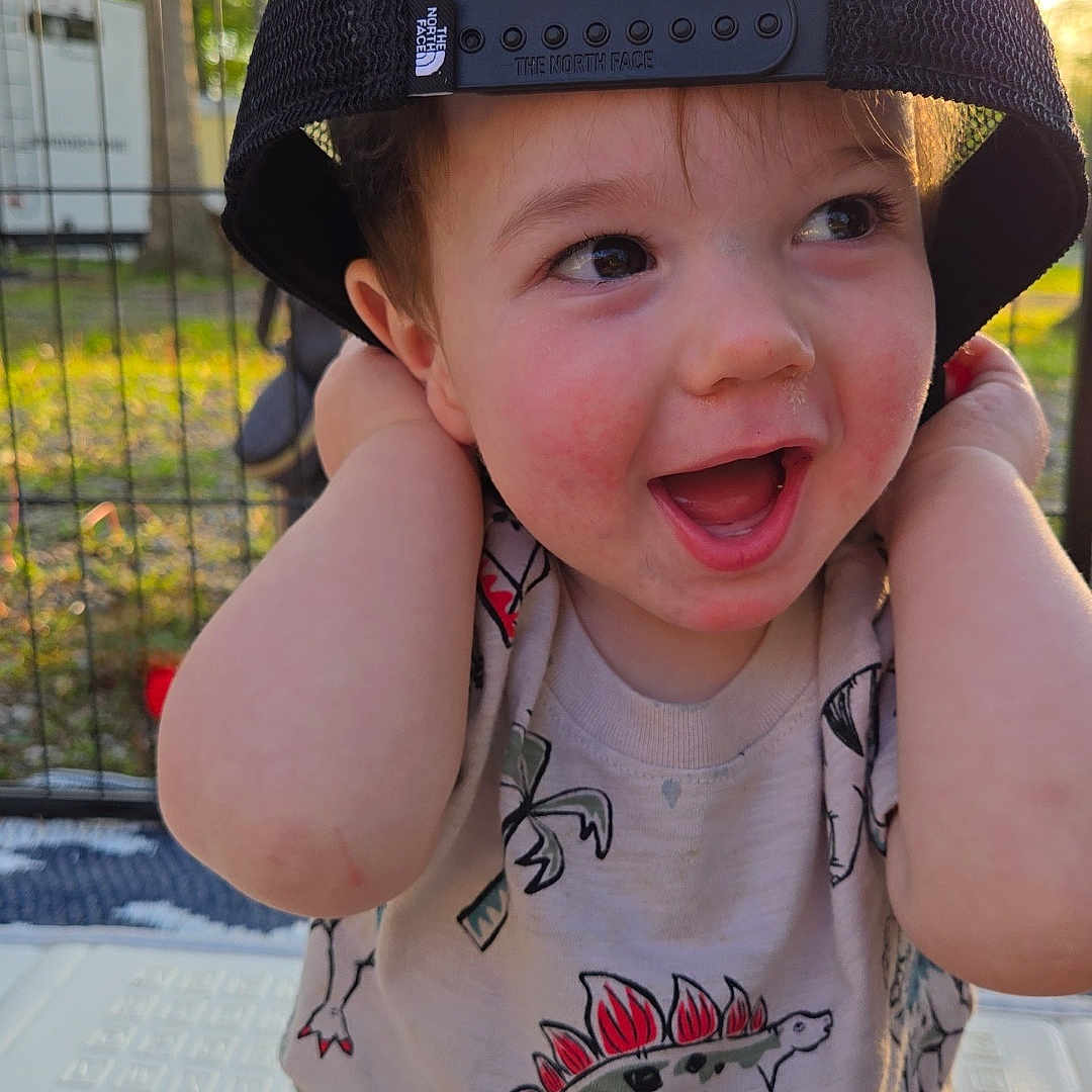 Bentley joined the competition — help win amazing prizes! baby, baseballcap, bodypart, cap, clothing, dress, face, finger, grass, hand, happy, hat, head, laughing, pants, person, photography, plant, portrait, t_shirt