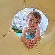 Bentley is registered to the contest to win money with this photo: baby, child, clothing, crawling, cute, daylight, expression, face, fun, hands, happy, head, indoor, person, play_structure, playground, smiling, toddler, toy, yellow