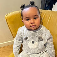 Keylia a rejoint le concours — aidez-le/la à gagner de superbes lots ! toddler, child, baby, yellow_chair, indoor, pigtails, curly_hair, grey_outfit, bear_design, cozy_clothing, wood_floor, wall, furniture, portrait, seated, cute, young_child, expression, person, comfortable