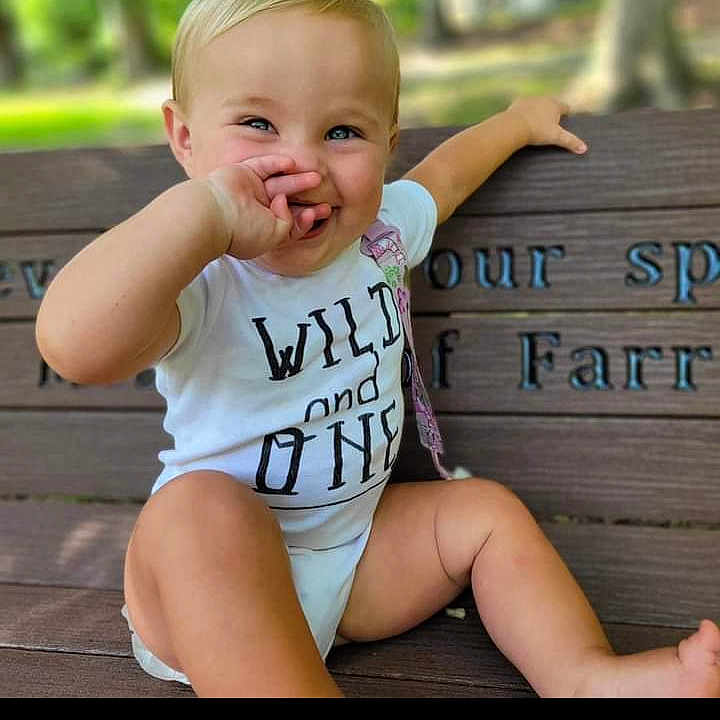 Harper is registered to the contest to win money with this photo: bench, bodypart, boy, child, clothing, face, furniture, grass, happy, head, male, mouth, person, photography, plant, portrait, shorts, sitting, t_shirt, teeth