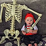 Jeremiah is registered to the contest to win money with this photo: skeleton, skull, baby, infant, child, pirate_costume, red_bandana, bones, prop, couch, patterned_blanket, bare_feet, cute, portrait, halloween, backyard, grass, plastic_skeleton, sitting, costume