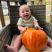 Jeremiah joined the competition — help win amazing prizes! baby, infant, pumpkin, overalls, wicker_chair, porch, outdoor, smile, happy, laughing, hands, feet, cushion, seasonal, autumn, orange, vegetable, sitting, portrait, cute
