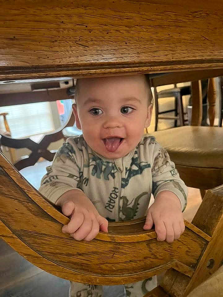Jeremiah joined the competition — help win amazing prizes! baby, child, clothing, cute, dinosaur_pajamas, expression, eyes, face, floor, furniture, hands, home, indoors, person, playful, smiling, toddler, tongue_out, wood, wooden_chair