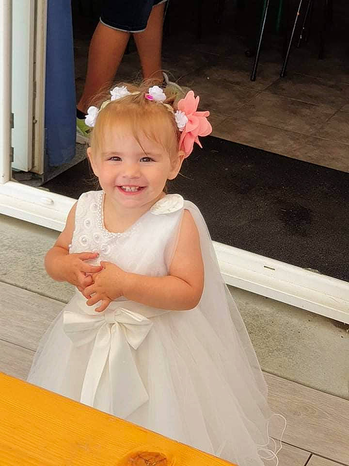 Maëline a rejoint le concours — aidez-le/la à gagner de superbes lots ! baby_toddler_clothing, bridal_accessory, child, dress, embellishment, facial_expression, flash_photography, flower, formal_wear, gesture, hair, happy, headpiece, joy, person, petal, pink, shoulder, skin, smile