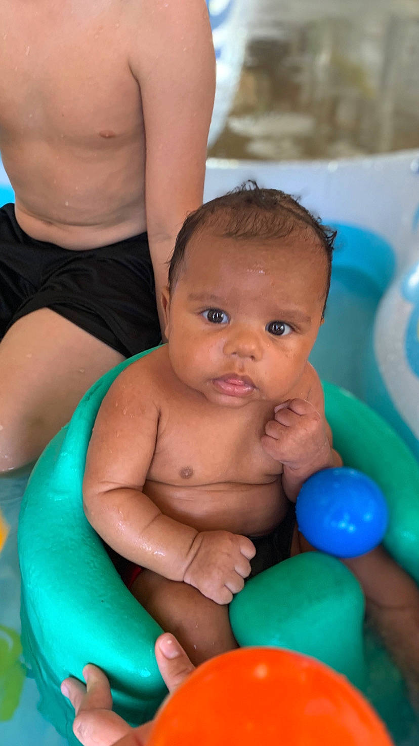 Kingston is registered to the contest to win money with this photo: baby, baby_playing_with_toys, bathing, black, blue, child, facial_expression, fun, happy, head, human, leisure, organ, people, person, photograph, skin, summer, toddler, toy