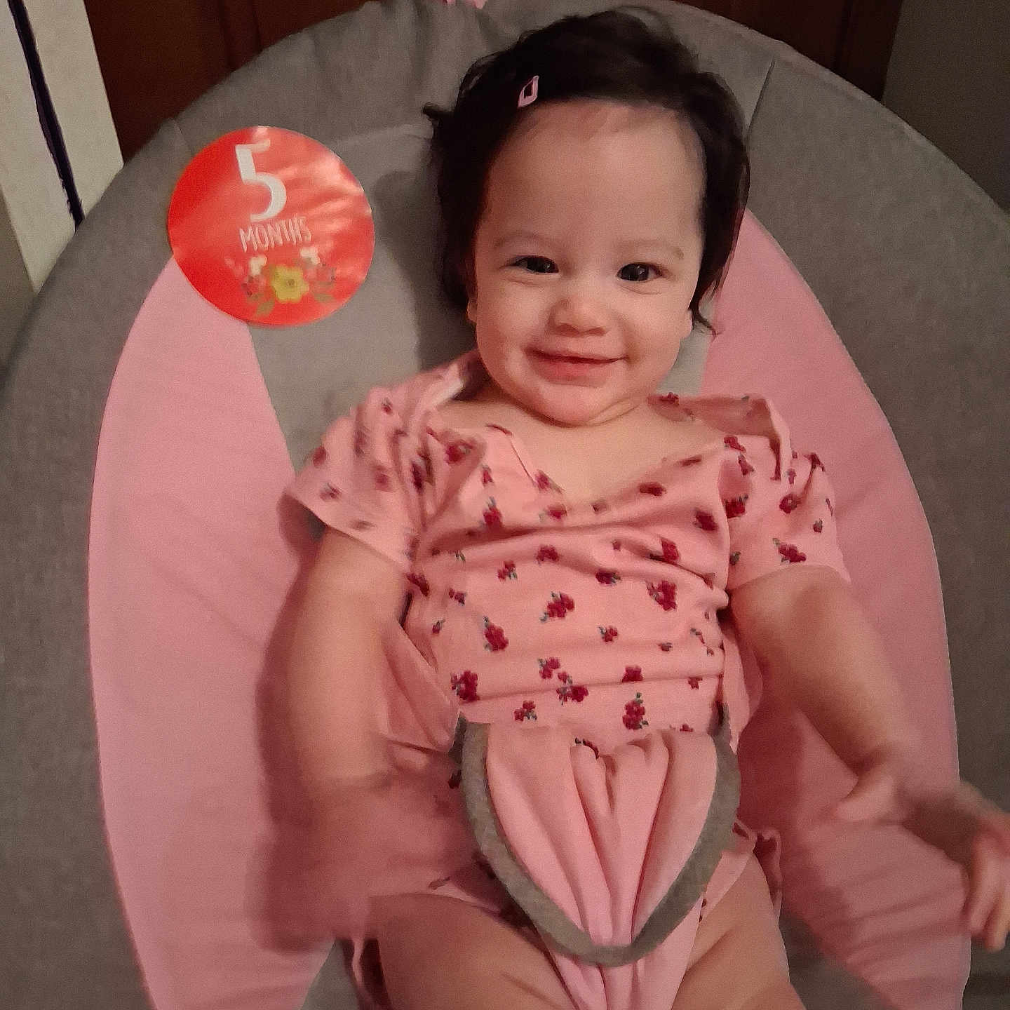 Malaya is registered to the contest to win money with this photo: baby, child, infant, smiling, pink_clothing, baby_seat, hair_clip, indoor, person, cute, happy, face, sitting, onesie, young_child, 5_months, skin, furniture, cushion, portrait