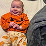 Emory is registered to the contest to win money with this photo: baby, blanket, cheeks, clothing, cozy, cute, face, fall_theme, hands, happy, head, indoors, infant, lying_down, orange_shirt, pattern, person, pumpkin_print, smiling, soft_texture