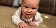 Emory is registered to the contest to win money with this photo: baby, blurred_background, carpet, child, cozy, crawling, cute, floor, furniture, hand, happy, head, home, indoors, infant, living_room, person, skin, sleeve, smiling