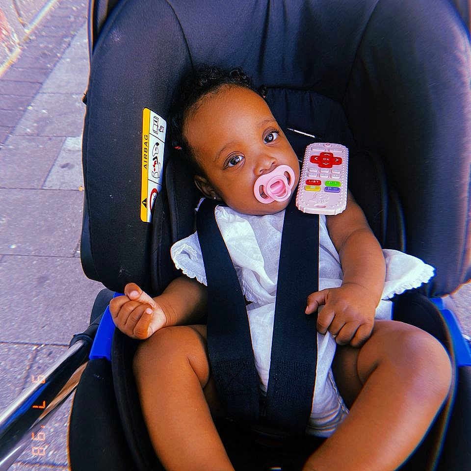 Noa-Rai joined the competition — help win amazing prizes! baby, bare_feet, black_stroller, child, curly_hair, cute, daylight, infant, infant_seat, outdoor, pacifier, pavement, portrait, relaxed, seatbelt, sidewalk, small_hands, stroller, toy_remote, white_clothing