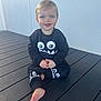 Kyson is registered to the contest to win money with this photo: toddler, child, barefoot, black_clothing, blue_eyes, smiling, sitting, wooden_deck, outdoor, playful_design, monster_face, long_sleeves, pants, young_child, cute, happy, person, casual, daylight, wall