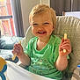 baby_food, blonde_hair, casual_clothing, child, curtain, fence, green_shirt, happy, high_chair, home, indoor, person, plastic_bottle, portrait, smiling, snack, sunlight, table, toddler, window