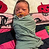 newborn, baby, infant, swaddled, pacifier, portrait, face, eyes, sleepy, lying_down, blanket, bed, textile, green_clothing, pink, black, colorful, indoors, close_up, photography