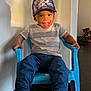 Samuel participe au concours pour gagner de l'argent avec cette photo : toddler, child, smiling, hat, anime, plastic_chair, striped_shirt, jeans, socks, mismatched_socks, indoor, happy, young_child, casual_clothing, seated, playful, portrait, home, floor, wall