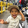 toddler, child, smiling, hat, beige_cap, white_shirt, patterned_shirt, shopping_store, clothing_rack, shoes, happy, portrait, indoor, floor, casual_clothing, boy, joyful, cute, retail, aisle
