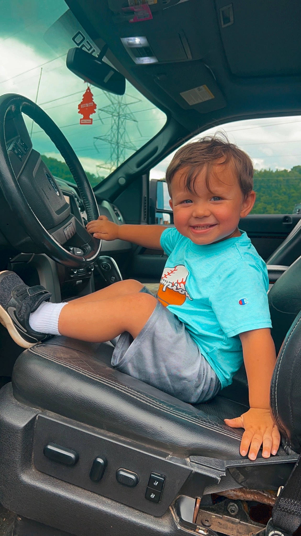 Winston is registered to the contest to win money with this photo: auto_part, automotive_design, automotive_exterior, automotive_window_part, car, car_seat, car_seat_cover, comfort, head_restraint, hood, joy, leg, mode_of_transport, motor_vehicle, person, personal_luxury_car, smile, steering_part, steering_wheel, toddler