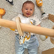 Mayron participe au concours pour gagner de l'argent avec cette photo : baby, child, clothing, cute, face, floor, happy, head, indoor, infant, jeans, patterned, person, playmat, playtime, smiling, socks, soft_toy, toy, wooden_toy