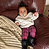 baby, pacifier, couch, leather, blanket, sweater, leggings, boots, indoor, child, person, plush, cozy, cute, portrait, smiling, hair, furniture, relaxing, home