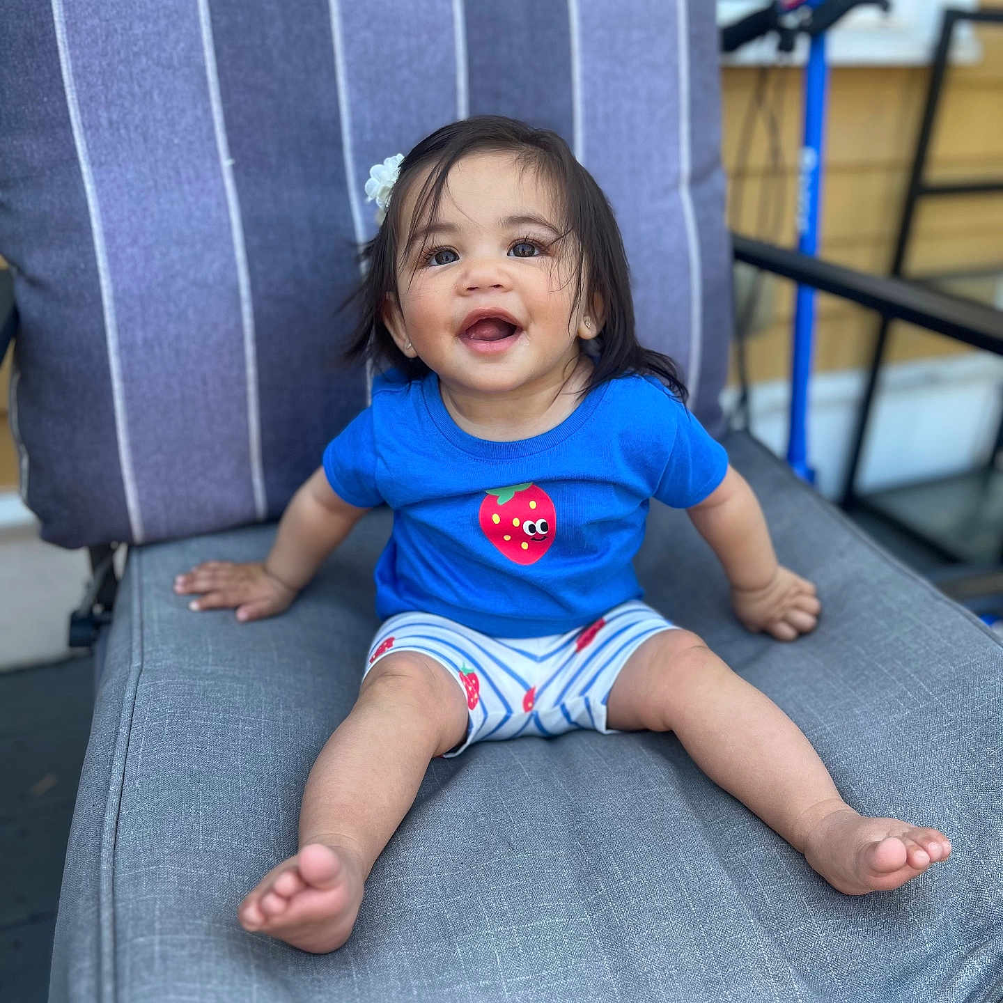 Eliana joined the competition — help win amazing prizes! toddler, child, smiling, blue_shirt, strawberry, hair_clip, chair, cushion, outdoor, scooter, happy, barefoot, shorts, person, portrait, seat, casual, daylight, cute, young_child