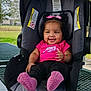 baby, smiling, pink_bow, pink_socks, car_seat, outdoor, picnic_table, child, happy, toddler, clothing, seat, person, park, nature, accessory, cute, infant, daylight, playful