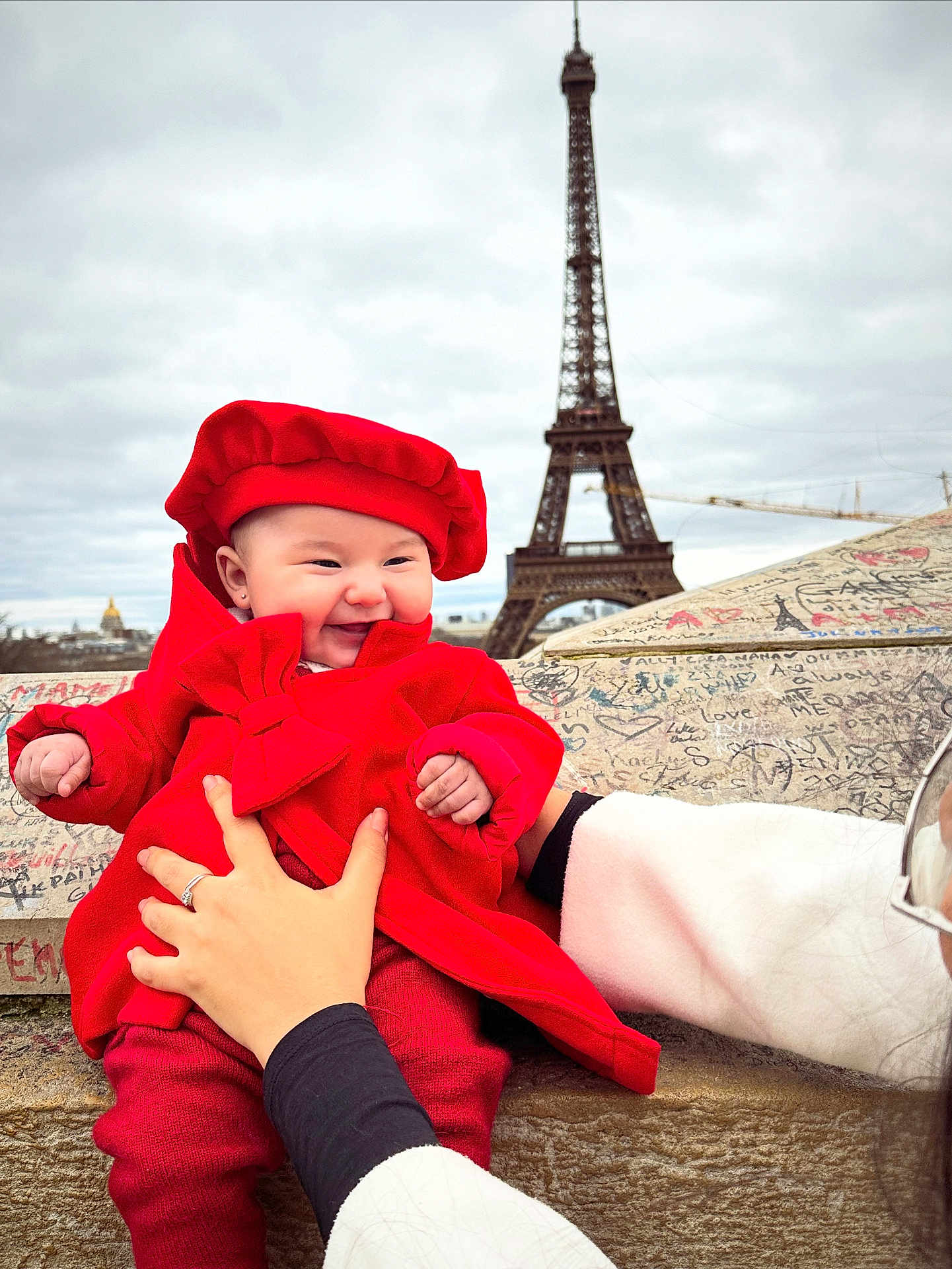 Gabriela participe au concours pour gagner de l'argent avec cette photo : baby, infant, child, red_coat, red_beret, smiling, happy, eiffel_tower, paris, landmark, graffiti, stone_ledge, hands, adult_hand, outdoor, cloudy_sky, portrait, travel, tourist, hat
