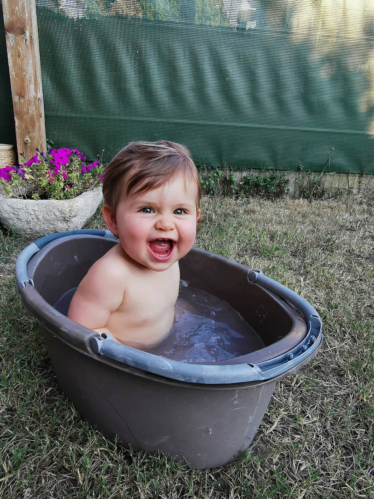 Anna participe au concours pour gagner de l'argent avec cette photo : baby, baby_bathing, baby_products, bathing, bathtub, child, face, fluid, fun, garden, grass, hand, happy, leisure, person, plant, sitting, smile, toddler, tree