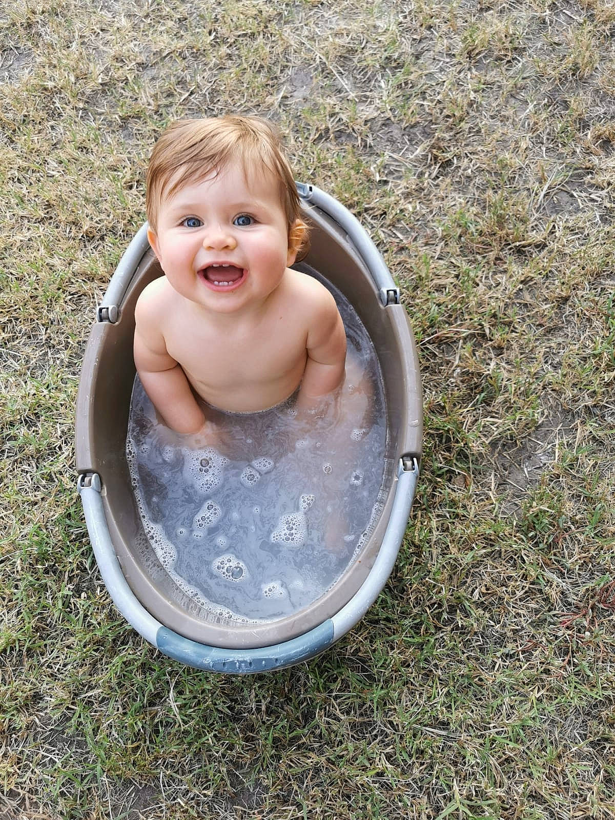 Anna participe au concours pour gagner de l'argent avec cette photo : baby, baby_products, baby_toddler_clothing, bathing, child, circle, eye, face, fluid, fun, grass, happy, leisure, people_in_nature, person, recreation, sitting, smile, toddler