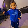 toddler, child, blue_jacket, puma, tracksuit, indoor, floor, smiling, walking, shoes, person, young_child, happy, short_hair, sporty_clothing, casual, portrait, standing, concrete_floor, modern_interior