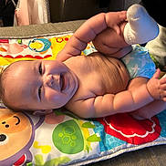 Celestia is registered to the contest to win money with this photo: baby, smiling, chubby, play_mat, colorful, diaper, sock, indoor, happy, cute, child, infant, lying_down, hands, feet, face, skin, fun, joy, person