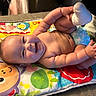 baby, smiling, chubby, play_mat, colorful, diaper, sock, indoor, happy, cute, child, infant, lying_down, hands, feet, face, skin, fun, joy, person