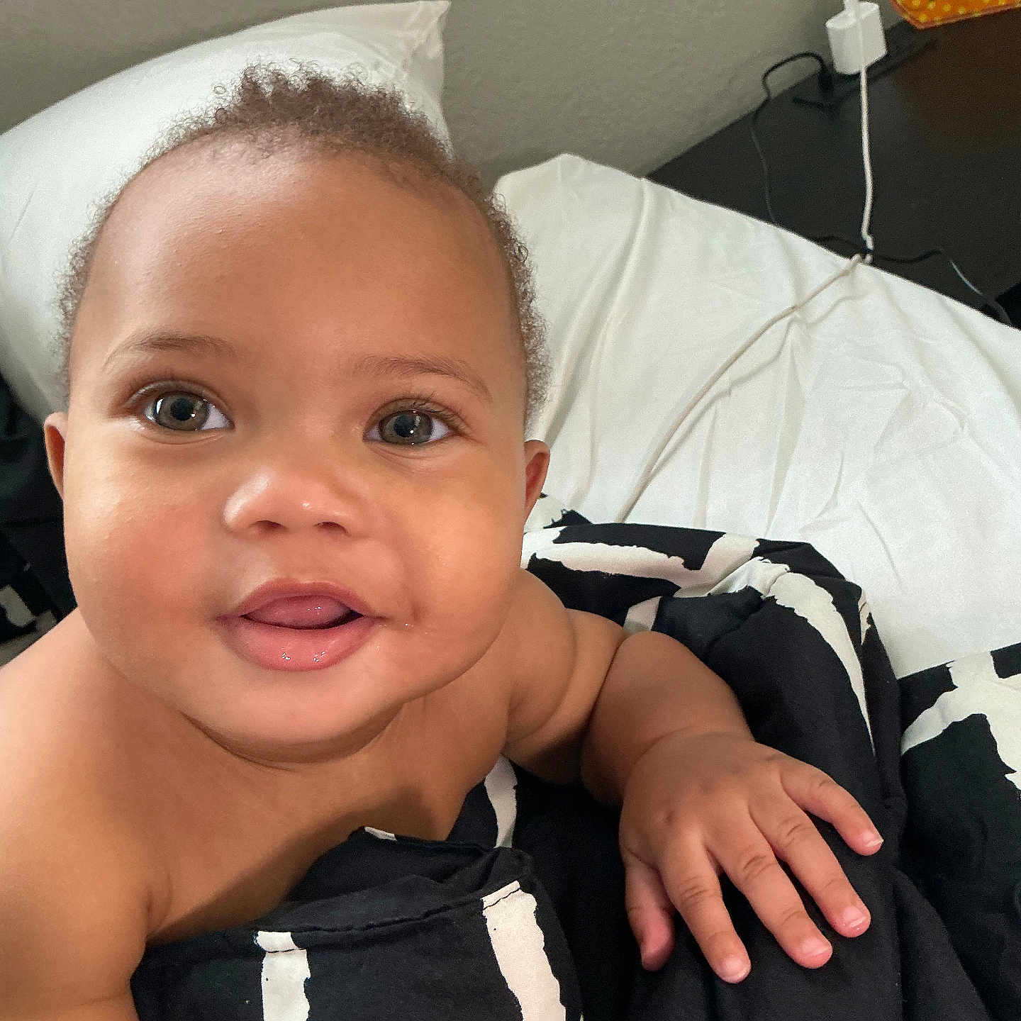 Asión is registered to the contest to win money with this photo: baby, bed, black, blanket, child, closeup, cute, eyes, face, furniture, hand, indoor, infant, mouth, pattern, pillow, skin, smiling, white, young