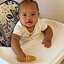 Asión is registered to the contest to win money with this photo: baby, child, closeup, curly_hair, expression, face, food, furniture, hand, high_chair, indoor, messy, mouth, person, popsicle, seat, skin, table, wall, white_shirt