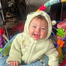 baby, child, smile, hoodie, fuzzy_clothing, baby_walker, toy, indoor, happy, face, infant, cute, playful, colorful, furniture, person, young_child, expression, seated, home