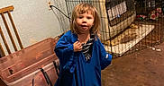 Oaklyn is registered to the contest to win money with this photo: blue_shirt, cardboard_box, casual_clothing, child, clutter, curious_expression, electrical_outlet, floor, heater, indoor, messy_room, oversized_clothing, person, plastic_bin, standing, toddler, toys, wall, wire_cage, young_child