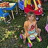 adult, backyard, barefoot, car_toy, casual_clothing, chair, child, grass, moana_tshirt, outdoor, person, plastic_toys, playtime, shade, stroller, summer, sunlight, table, toy_walker, tree
