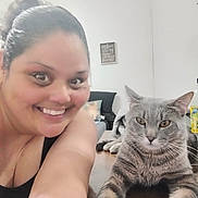 Smokey is registered to the contest to win money with this photo: woman, smile, cat, tabby_cat, indoor, table, furniture, happy, portrait, person, living_room, home, pet, animal, face, hair, couch, decor, relaxed, friendship
