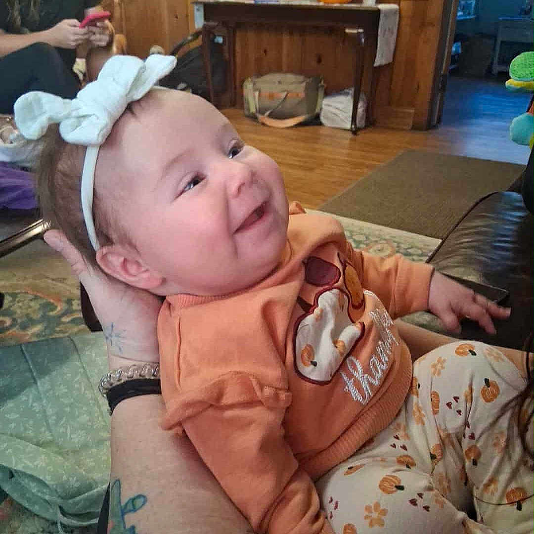 Kaitlyn Michelle joined the competition — help win amazing prizes! baby, child, smiling, headband, bow, tattoo, arm, woman, phone, wood_paneling, pumpkin, table, rug, couch, indoor, clothing, person, happy, floor, home