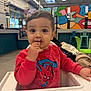 Kelyo a rejoint le concours — aidez-le/la à gagner de superbes lots ! toddler, child, high_chair, red_sweatshirt, spiderman, snack, chocolate, face, indoor, graffiti, mural, colorful, furniture, person, eating, hand, table, casual_clothing, young_child, cute