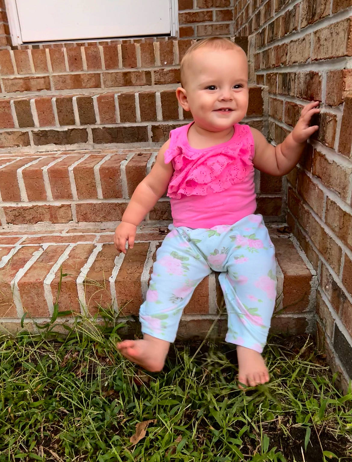 Kinsley is registered to the contest to win money with this photo: baby_toddler_clothing, barefoot, beauty, brick, brickwork, child, finger, fun, grass, hand, happy, joy, leg, people_in_nature, person, pink, shorts, skin, sleeve, smile