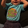 Tristian joined the competition — help win amazing prizes! baby, child, infant, smiling, blue_shirt, colorful_text, dark_pants, raising_arms, lying_down, happy, casual_clothing, indoors, person, portrait, cute, playful, young_child, toddler, relaxed, skin