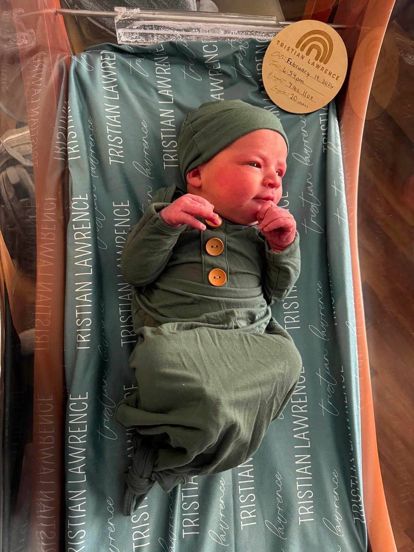 Tristian joined the competition — help win amazing prizes! newborn, baby, infant, hospital_bassinet, swaddle, knit_hat, green_clothing, wooden_buttons, blanket, name_tag, newborn_card, maternity, crib, portrait, closeup, sleepy, cheeks, hands, hospital_room, wrapped