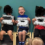 Sawyer is registered to the contest to win money with this photo: child, children, certificate, classroom, chair, laughing, smiling, award, education, kid, indoor, happy, wall, toy, furniture, person, shorts, shirt, footwear, celebration