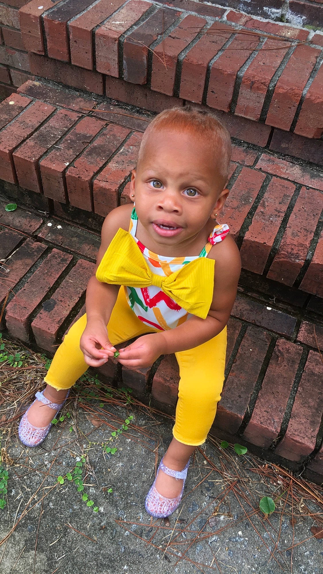 Liberty is registered to the contest to win money with this photo: baby_toddler_clothing, child, face, foot, grass, happy, head, human_leg, leg, leisure, magenta, people_in_nature, person, pink, sandal, sitting, skin, soil, thigh, toddler