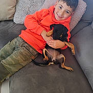 Coquillette participe au concours pour gagner de l'argent avec cette photo : boy, brown_eyes, camouflage_pants, casual_clothing, child, couch, cozy, dog, floor_tiles, happy, home, indoor, orange_hoodie, pet, pillow, puppy, relaxed, short_hair, smiling, young